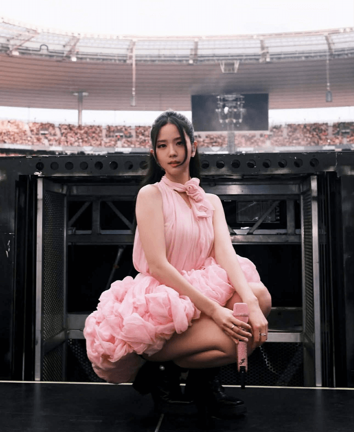 people-Jisoo (BLACKPINK)-A-pink ruffled dress-A-crouching pose-A-stage equipment-A-stadium crowd