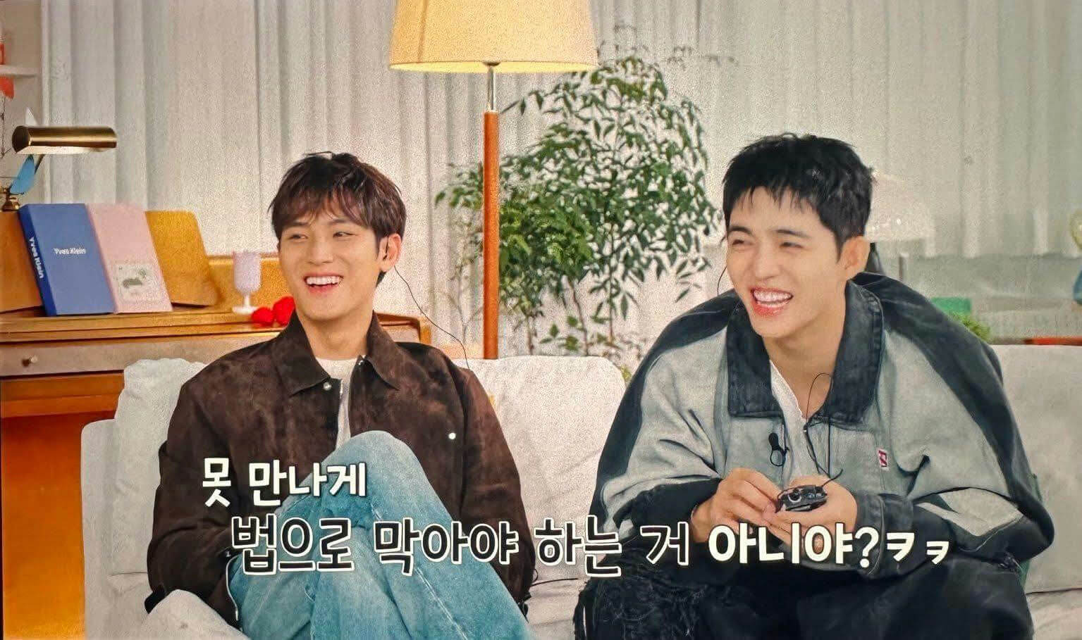 people-two men-A-smiling-A-laughing-B-sitting on a couch-B-holding a small black device-C-Korean subtitle text