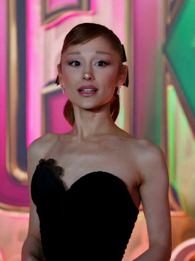 people-Ariana Grande-A-black strapless dress-A-pink and green lighting background-B-long eyelashes-C-hair tied back with black bows