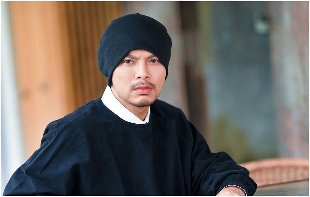 people-A-man-A-black-beanie-A-wearing-A-black-top-A-with-A-white-collar-A-staring-A-intently-A-outdoors