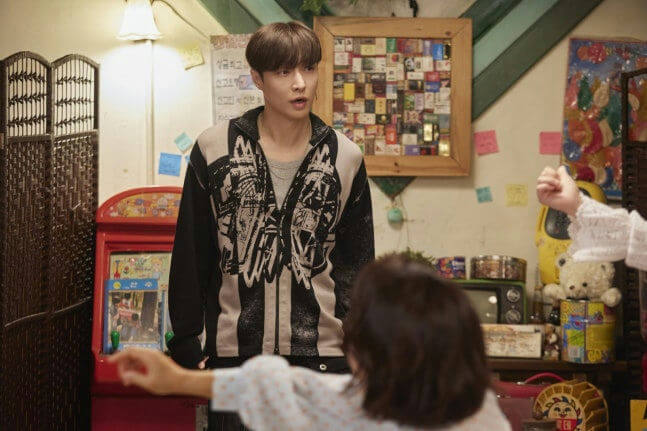 people-man in black and white hoodie-A-surprised expression-A-woman with dark hair in foreground-B-cluttered room-C-arcade machine