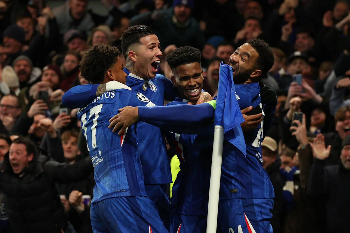 people-four-male-football-players-A-blue-jerseys-A-celebrating-A-joyful-expression-B-stadium-crowd-B-cheering-C-corner-flag