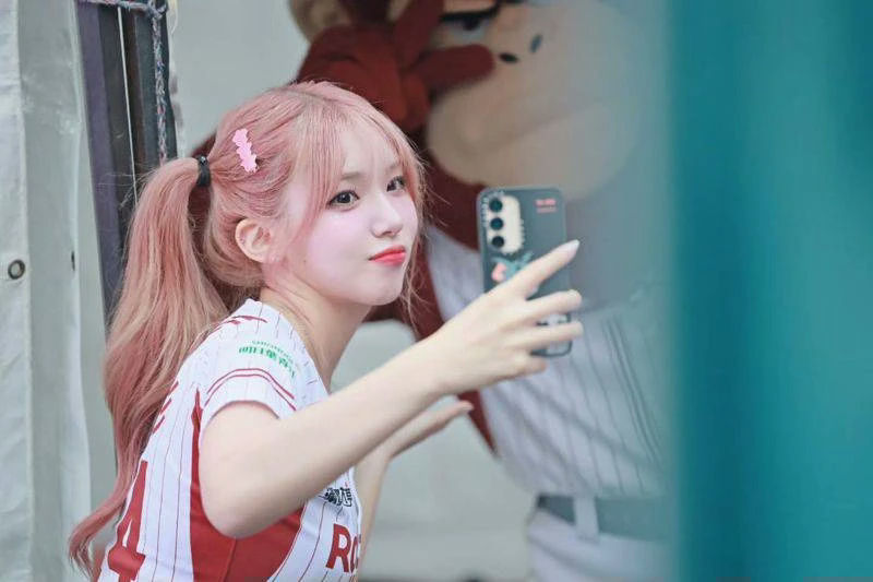 people-woman-pink hair-pigtails-taking selfie-baseball uniform-phone