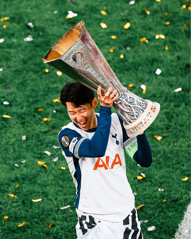 people-Son Heung-min-A-celebrating-A-holding trophy-A-Tottenham Hotspur jersey-B-confetti-C-green grass