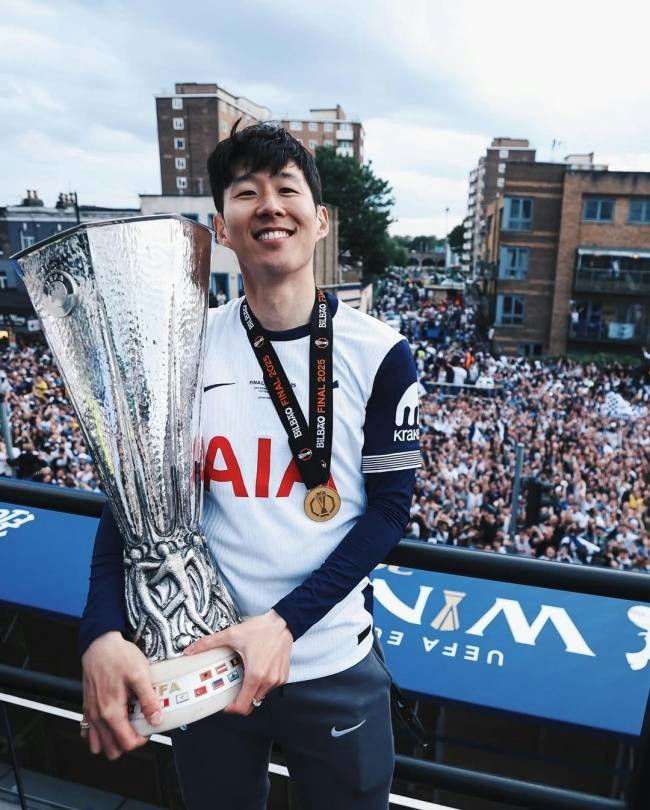 people-Son Heung-min-A-smiling-A-holding trophy-B-wearing Tottenham jersey-C-celebrating with fans