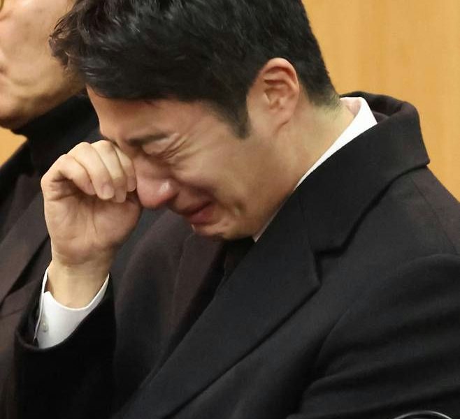 people-man-crying-man-black suit-man-hand to face-man-funeral setting