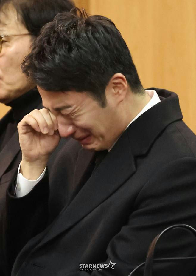 people-man-crying-man-black suit-man-hand to face-man-funeral setting