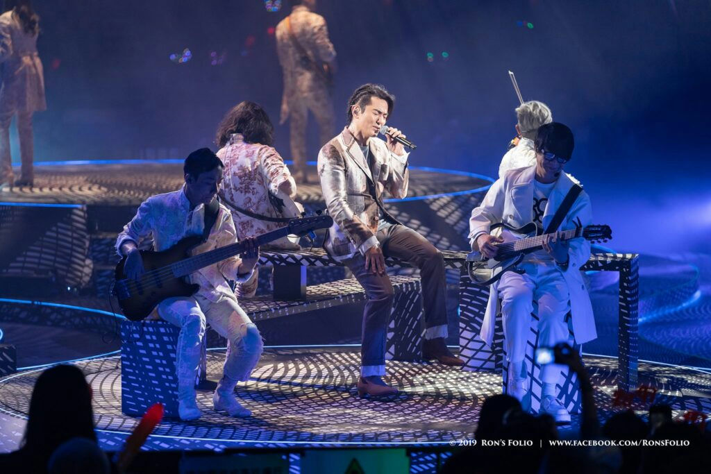 people-3-male singer-A-male bass player-A-male guitarist-A-male backing musician-A-male backing musician-A-audience member-B-stage-C-musical performance
