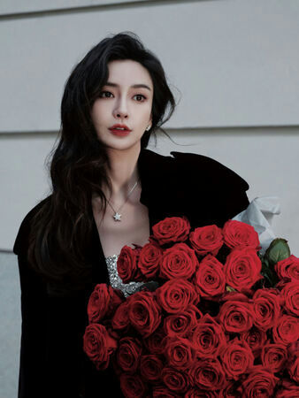people-woman-holding-a-large-bouquet-of-red-roses-wearing-a-black-outerwear-and-a-sparkly-top-with-a-star-necklace
