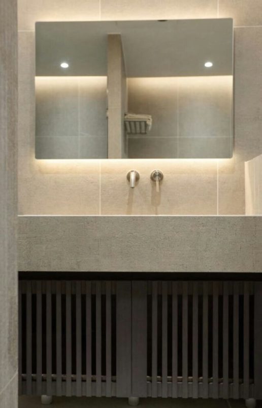 bathroom-A-modern-A-vanity-A-backlit-mirror-A-stone-sink-A-wall-mounted-faucets