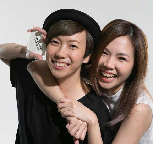 people-two women-hugging-smiling-holding card