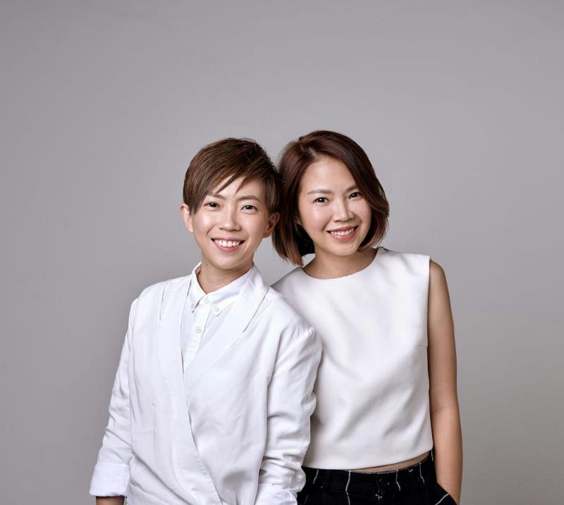people-Two women-smiling-wearing white tops-studio portrait-grey background