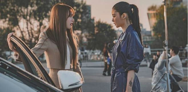 people-two women-A-confrontation-A-outdoor setting-A-car door-A-filming equipment