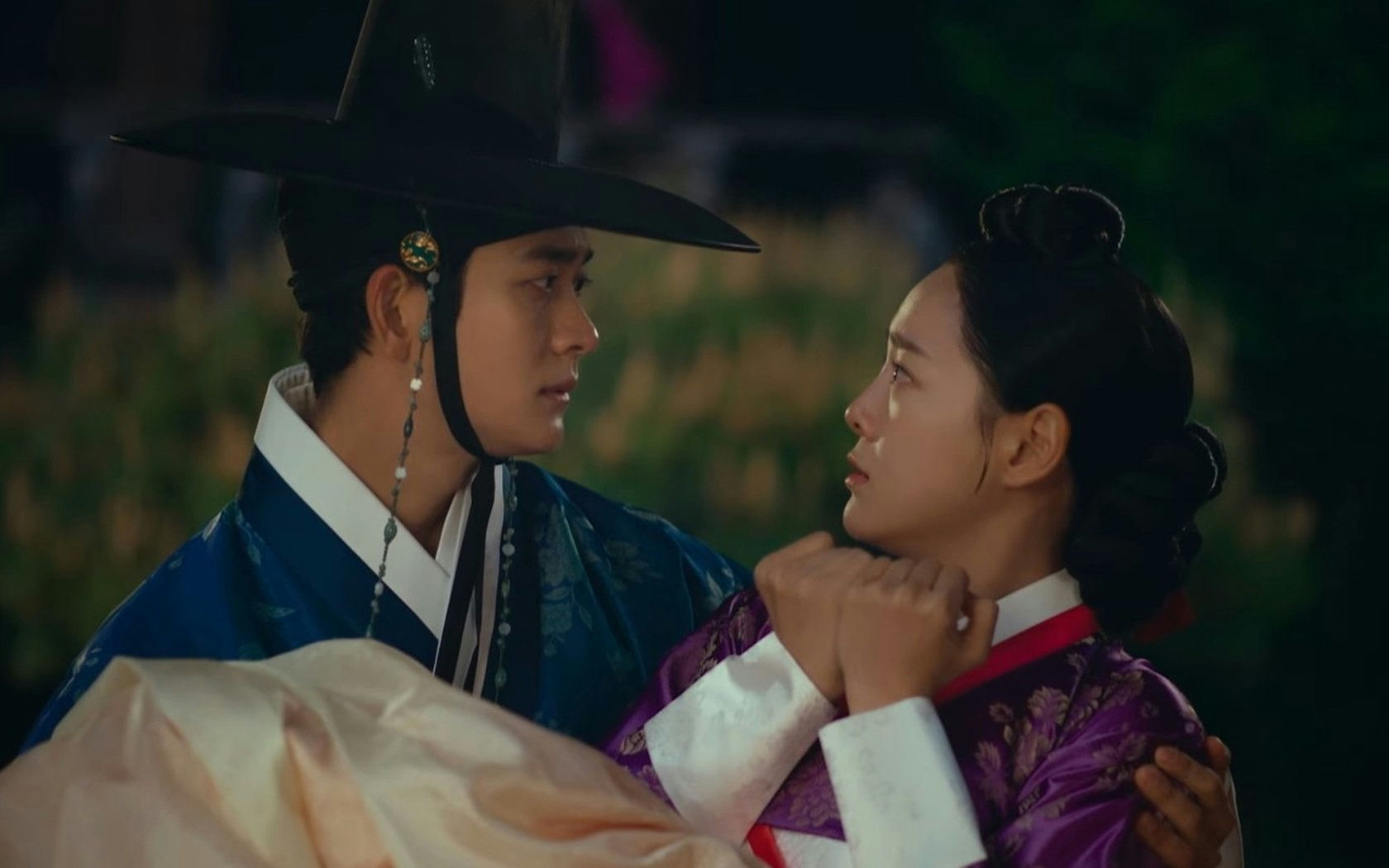 people-Man in traditional Korean hat and blue hanbok holding a woman-A-Woman in purple and white hanbok looking intently at the man-B-Intimate gaze between two people in historical Korean clothing-C-Romantic scene in a dark, outdoor setting