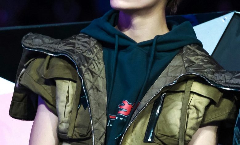 people-young man-A-looking up-A-brown shaggy hair-A-green hoodie-A-khaki quilted vest-A-light makeup scar