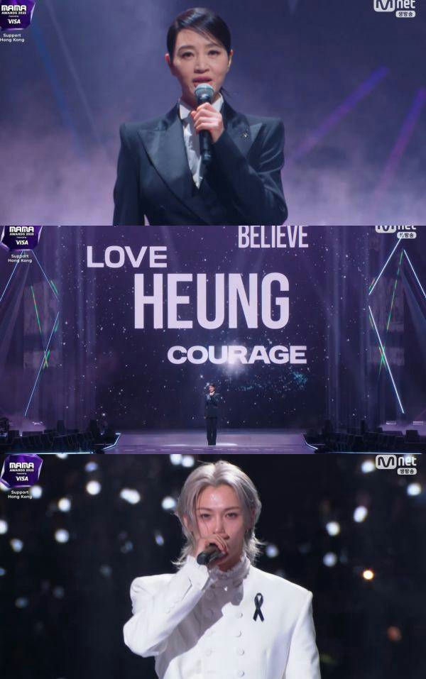 people-Woman in dark suit speaking into a microphone-Woman in dark suit speaking into a microphone-Stage screen with text 