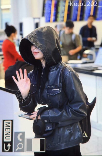 people-woman-leather jacket-hood up-waving-airport setting