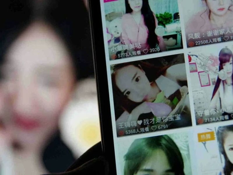 people-One person is holding a smartphone-Smartphone screen-Grid of video thumbnails-Chinese text and view counts