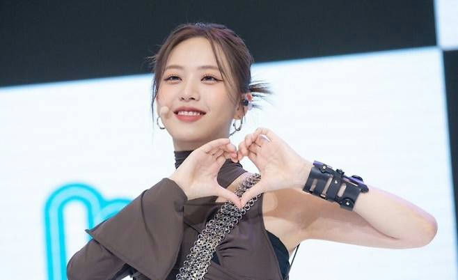 people-Young woman-Smiling-Making a heart gesture with hands-Wearing a dark brown top with chain detail-Wearing a black wrist cuff