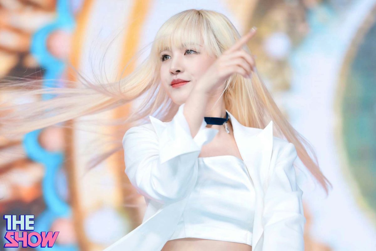 people-female performer-A-blonde hair-A-white outfit-A-pointing gesture-A-stage performance-B-K-pop idol-B-The Show logo-B-choker necklace-C