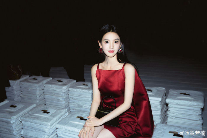 people-Chinese actress Zhang Ruonan-A-red satin dress-B-dark background-C-stacks of white packages