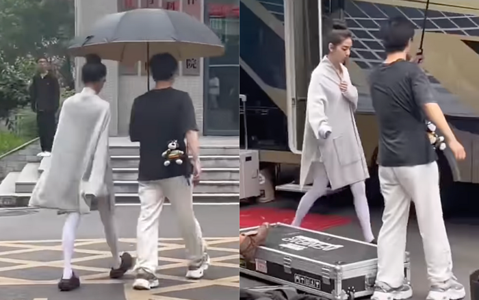 people-woman in white cape and leggings-man with black shirt and white pants-umbrella-large case near bus
