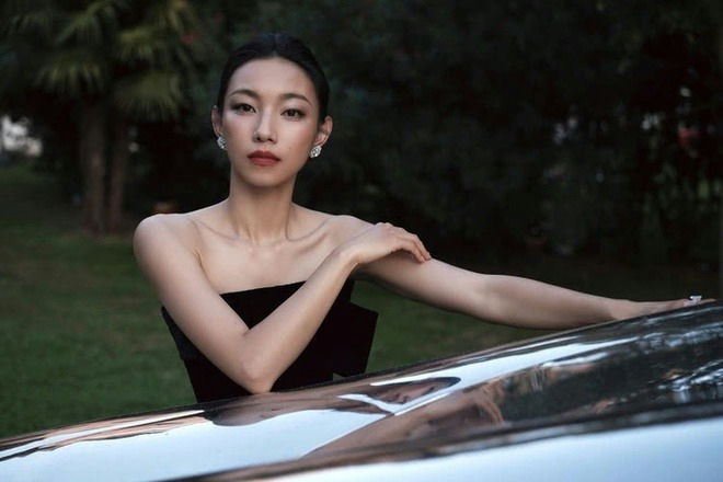 people-woman-A-black strapless dress-A-diamond earrings-A-leaning on reflective surface-A-outdoor setting