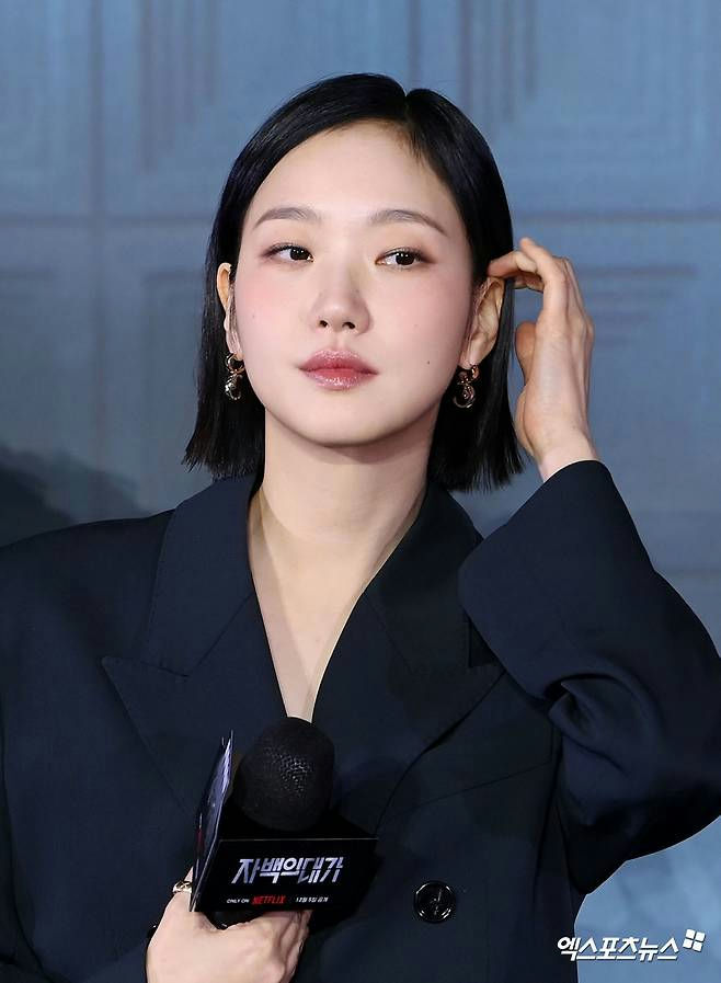 people-Korean actress Kim Go-eun-A-short black hair-A-dark blazer-B-holding a microphone with Korean text-C-gold hoop earrings