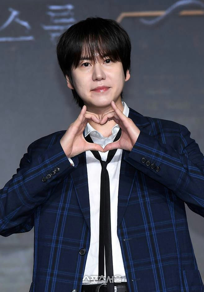 people-one male-gesture-finger heart-attire-plaid suit-expression-smiling