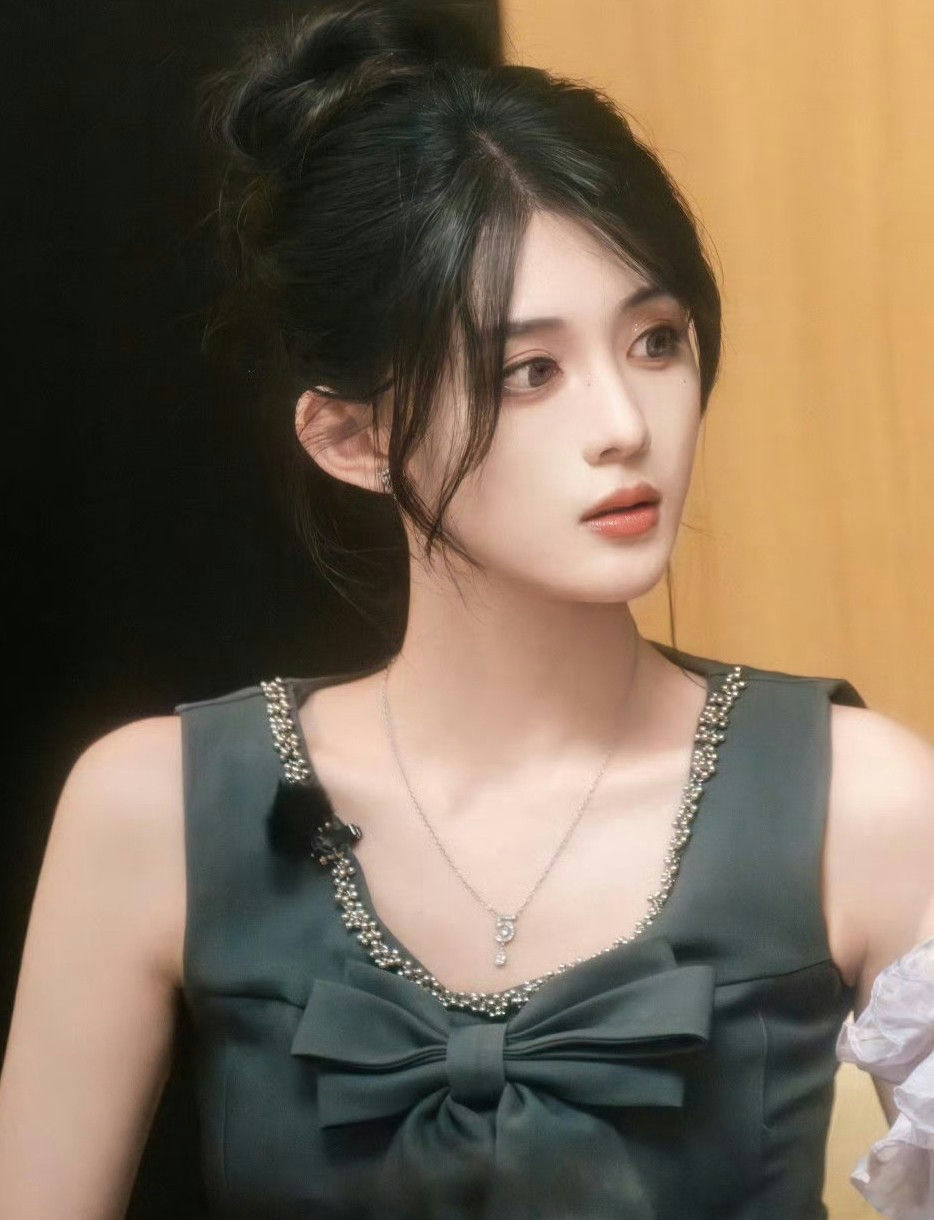 people-woman-A-dark hair-A-updo hairstyle-A-sleeveless dress-A-bow detail-A-beaded trim-A-silver necklace-A-looking away
