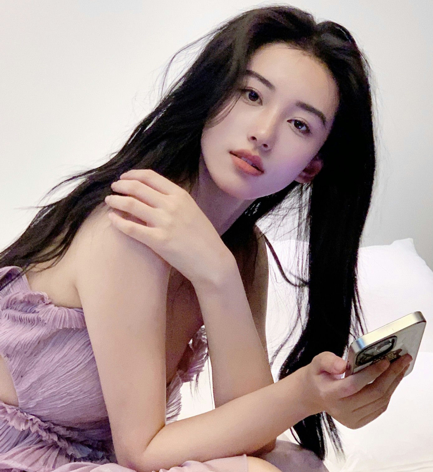 people-woman-A-long black hair-A-lavender dress-A-holding phone-A-light background