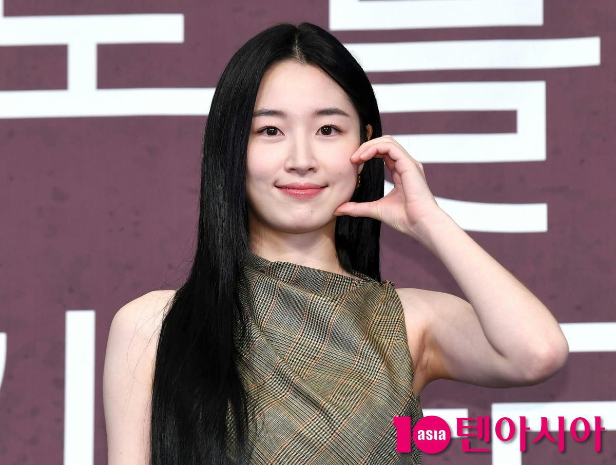 people-woman-A-long black hair-B-plaid sleeveless top-C-making a gesture near her cheek