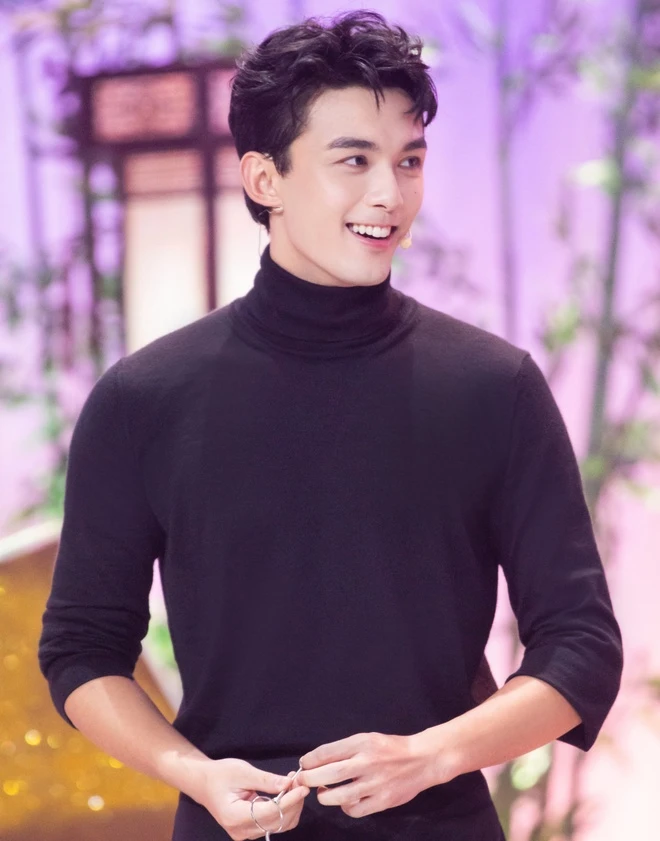 people-man-smiling-A-black turtleneck sweater-B-holding small scissors-C-stage background