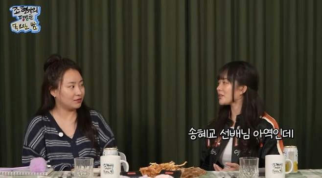 people-two women sitting at a table-conversation-Korean text overlays-dark green curtain background