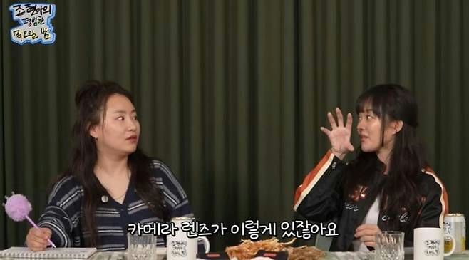 people-two women-sitting at table-Korean subtitles-woman on right gesturing with hand