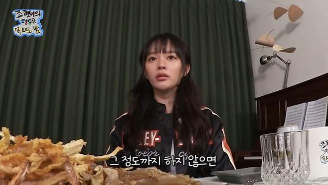 people-woman-A-dark hair with bangs-B-eating dried shredded squid-C-wearing a black and orange racing jacket