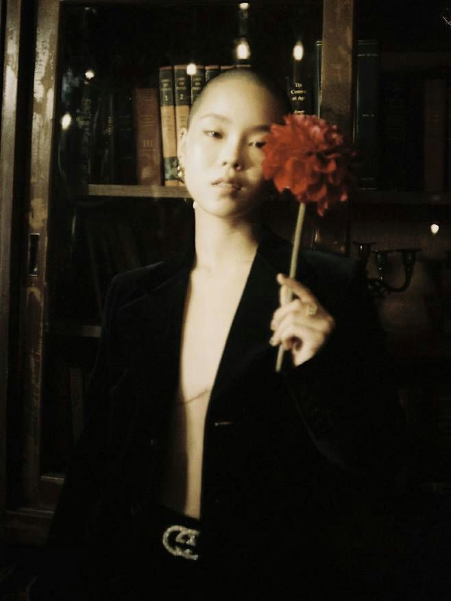 people-woman-A-shaved head-A-holding red flower-B-black velvet jacket-C-Gucci belt buckle