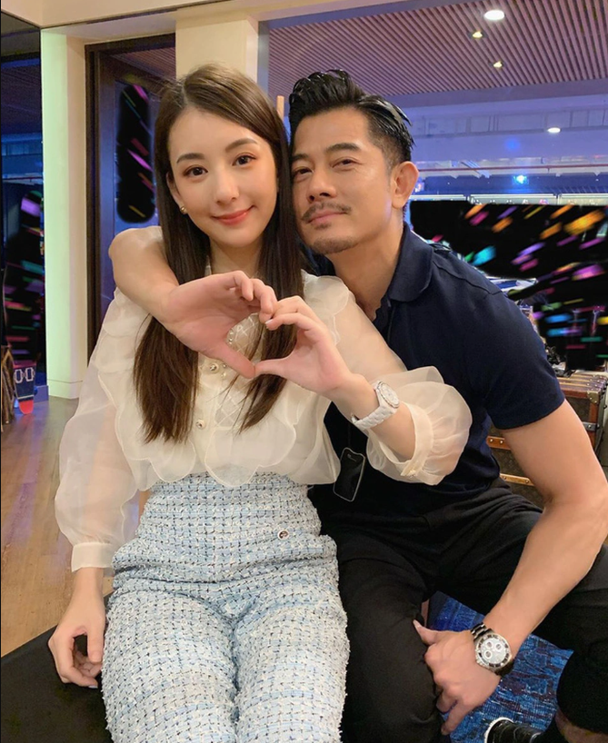 people-woman and man-posing together-A-hand heart gesture-B-smiling-C-wearing stylish clothes