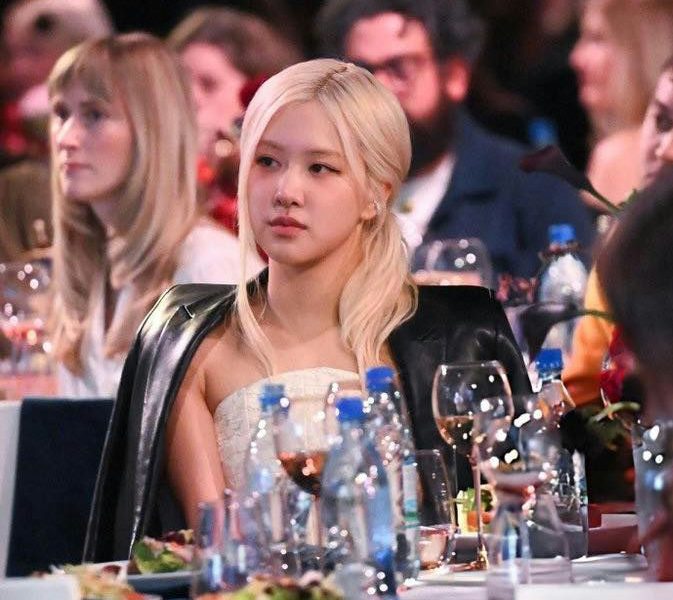 people-Rosé (BLACKPINK)-blonde hair-attending event-seated at table-wearing leather jacket