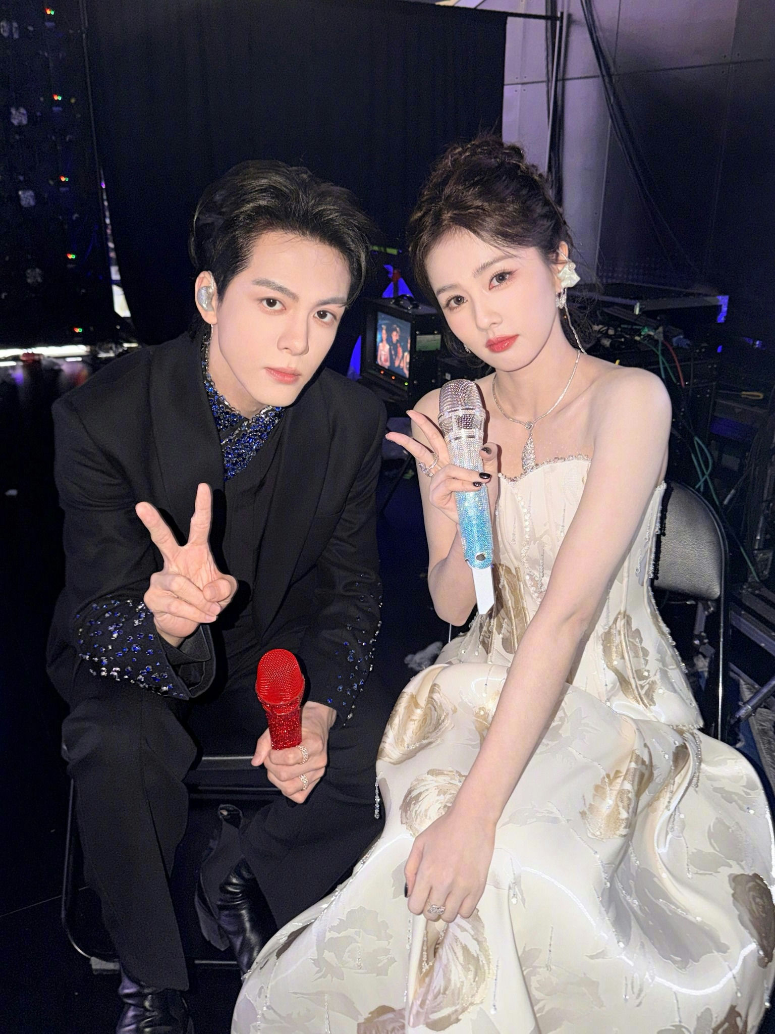 people-two-Asian-man-and-woman-sitting-microphone-bling-man-wearing-black-suit-woman-wearing-white-gown-peace-sign