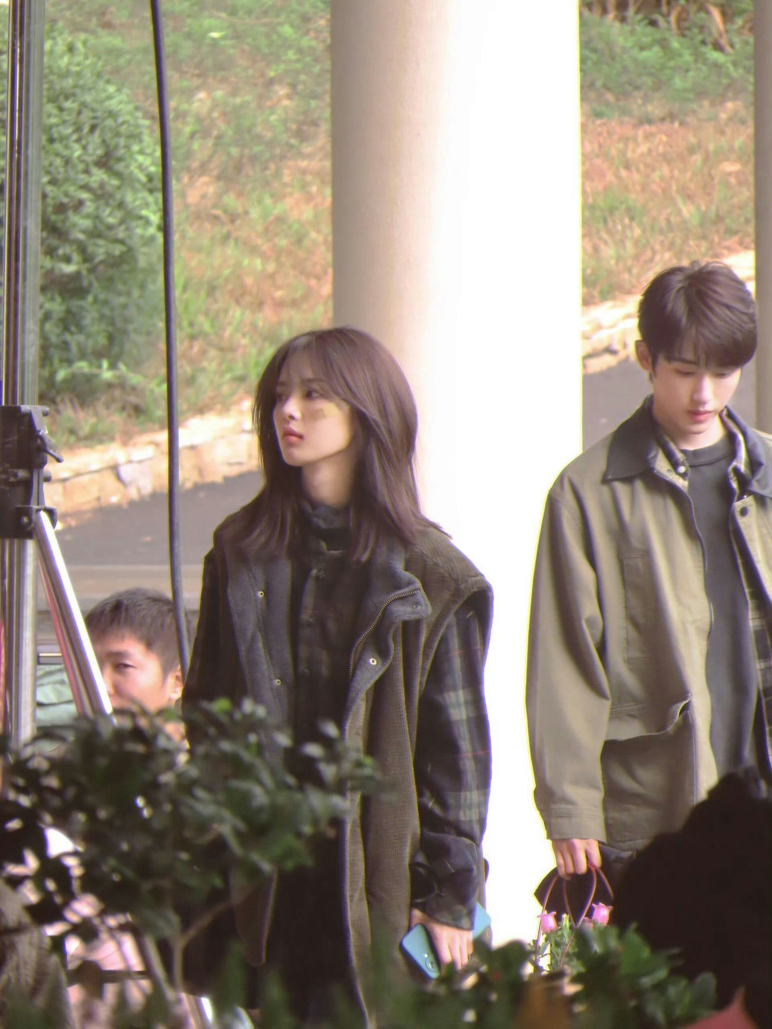 people-woman-long dark hair-man-outdoor setting-film set equipment-plants