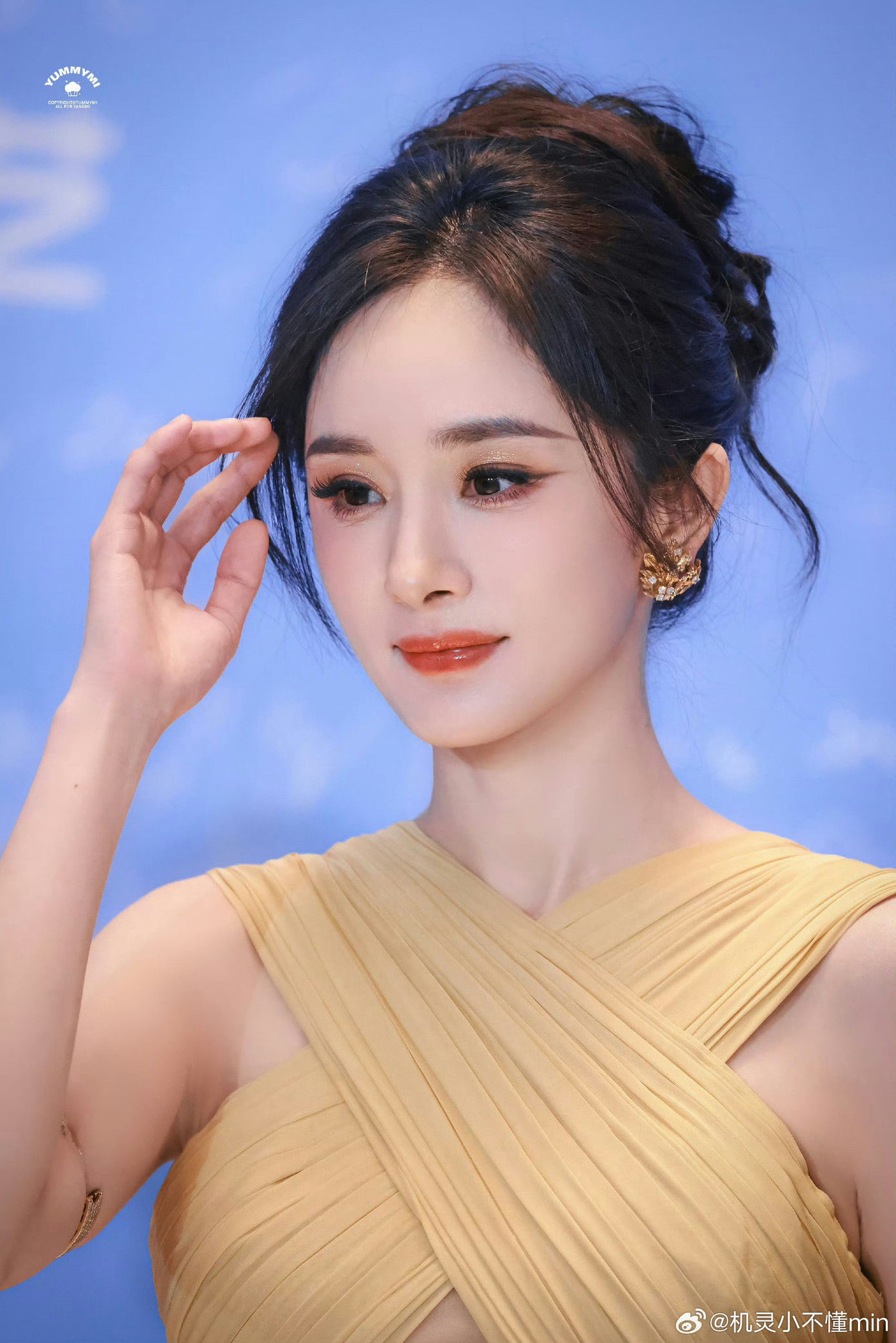 people-woman-A-yellow dress-A-updo hairstyle-A-blue background-A-gold earrings