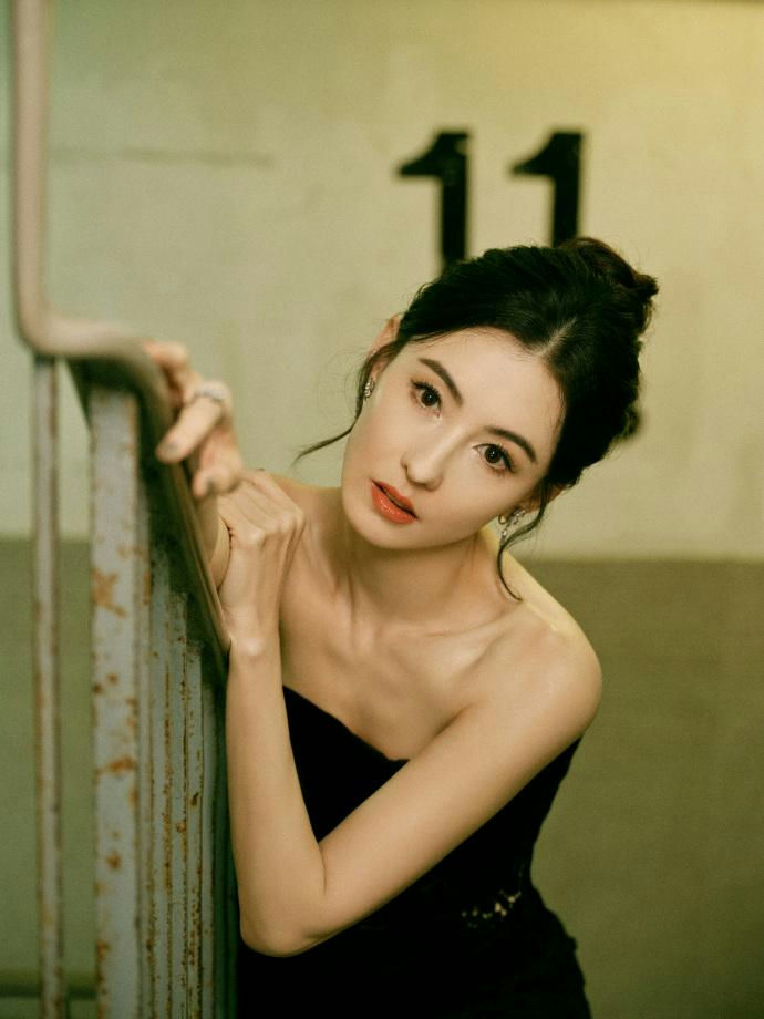 people-woman-A-strapless black dress-A-leaning on railing-A-indoor setting-A-number 11 visible
