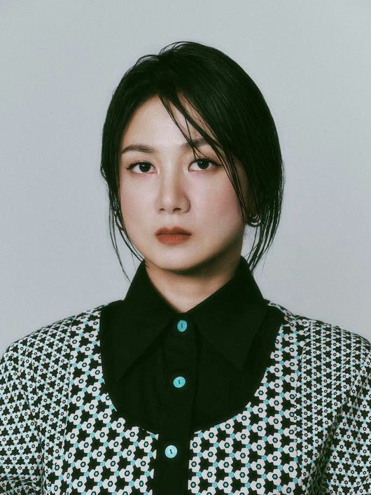 people-Woman-Asian-Hairstyle-Short black hair-Attire-Patterned cardigan over black collared shirt-Facial Expression-Serious/Neutral