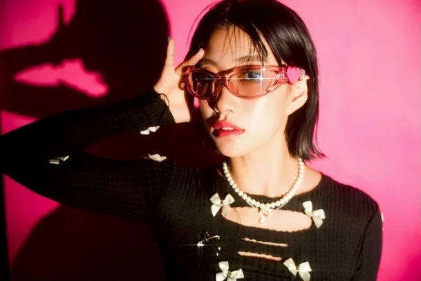 people-young woman-A-pink background-B-pink wraparound sunglasses-C-black top with white bows