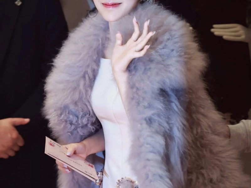 people-woman-A-smiling-A-wearing fur stole-B-holding card-C-event entrance