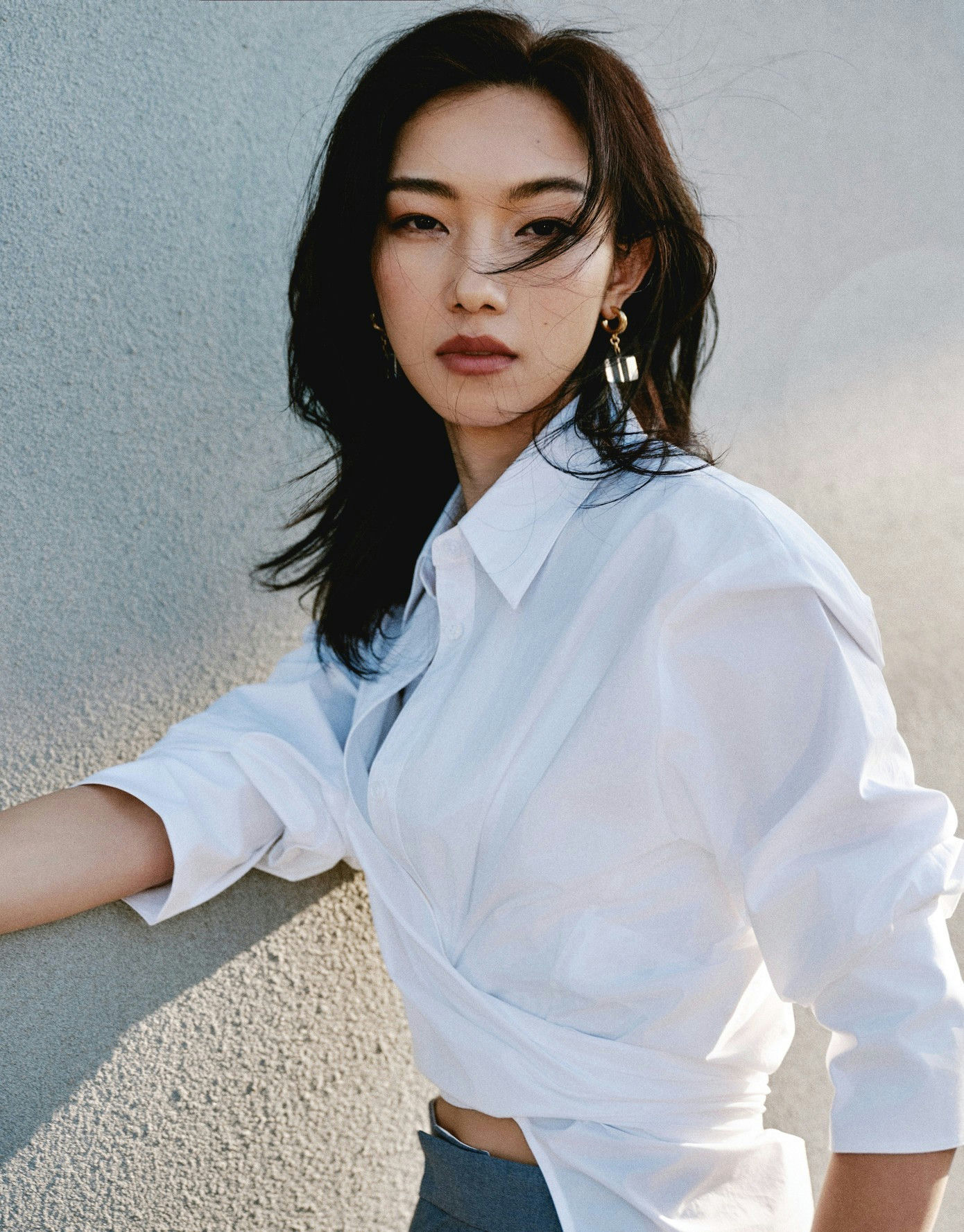 people-One woman-A-Asian-A-dark hair-A-white wrap shirt-B-gold earrings-C-textured wall