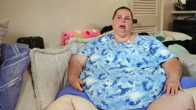 people-woman-sitting-on-couch-looking-surprised-wearing-blue-tie-dye-shirt