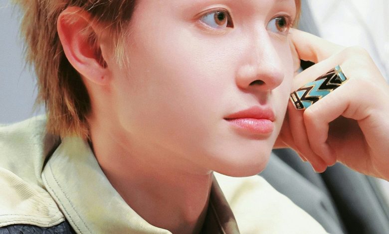 people-one male-A-blond spiky hair-A-light skin-A-brown eyes-B-looking away-B-wearing patterned ring-C-wearing black textured vest over light collar-C