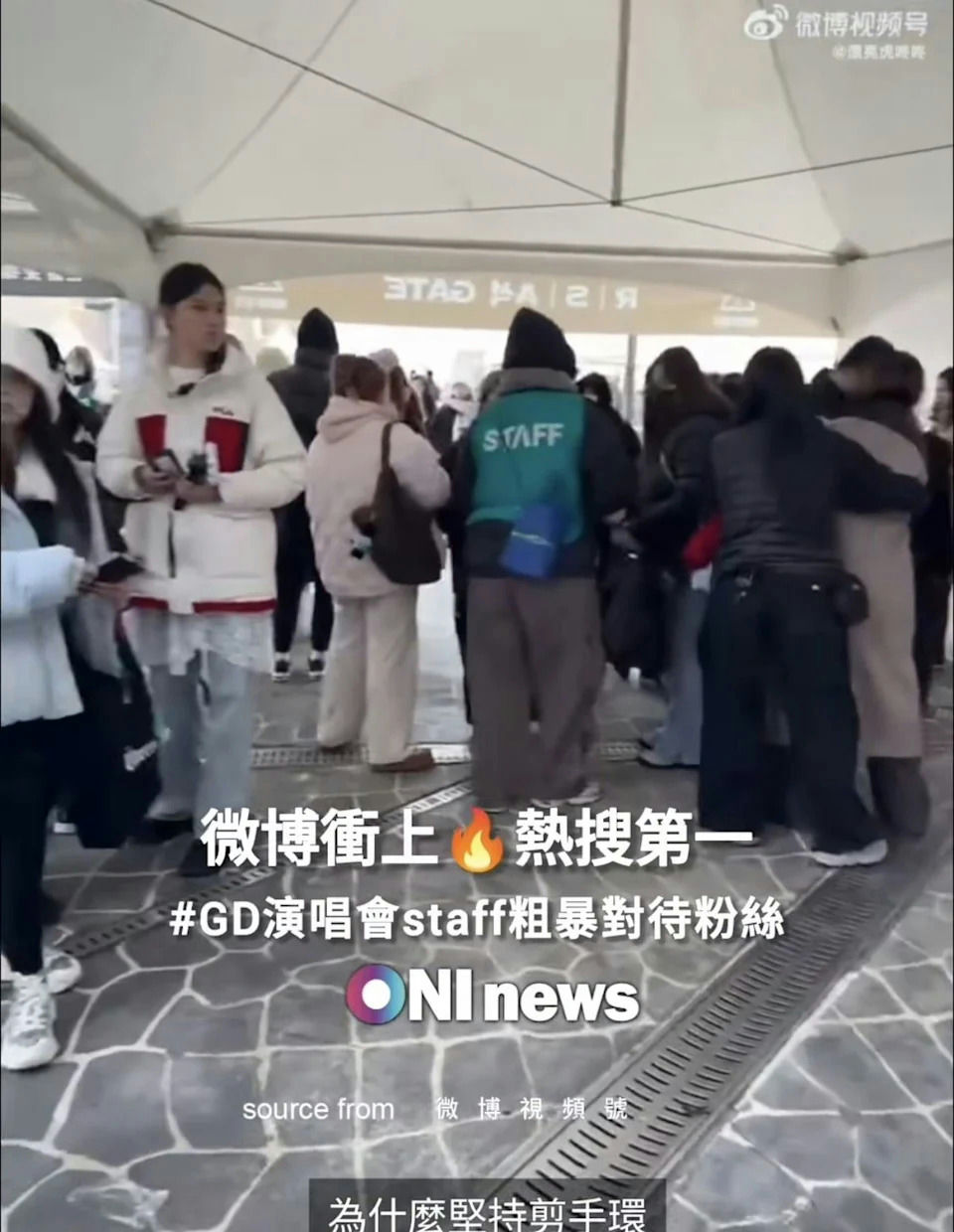 people-Several people standing in a queue or crowd outdoors-venue entrance-A-staff member wearing a teal vest with 